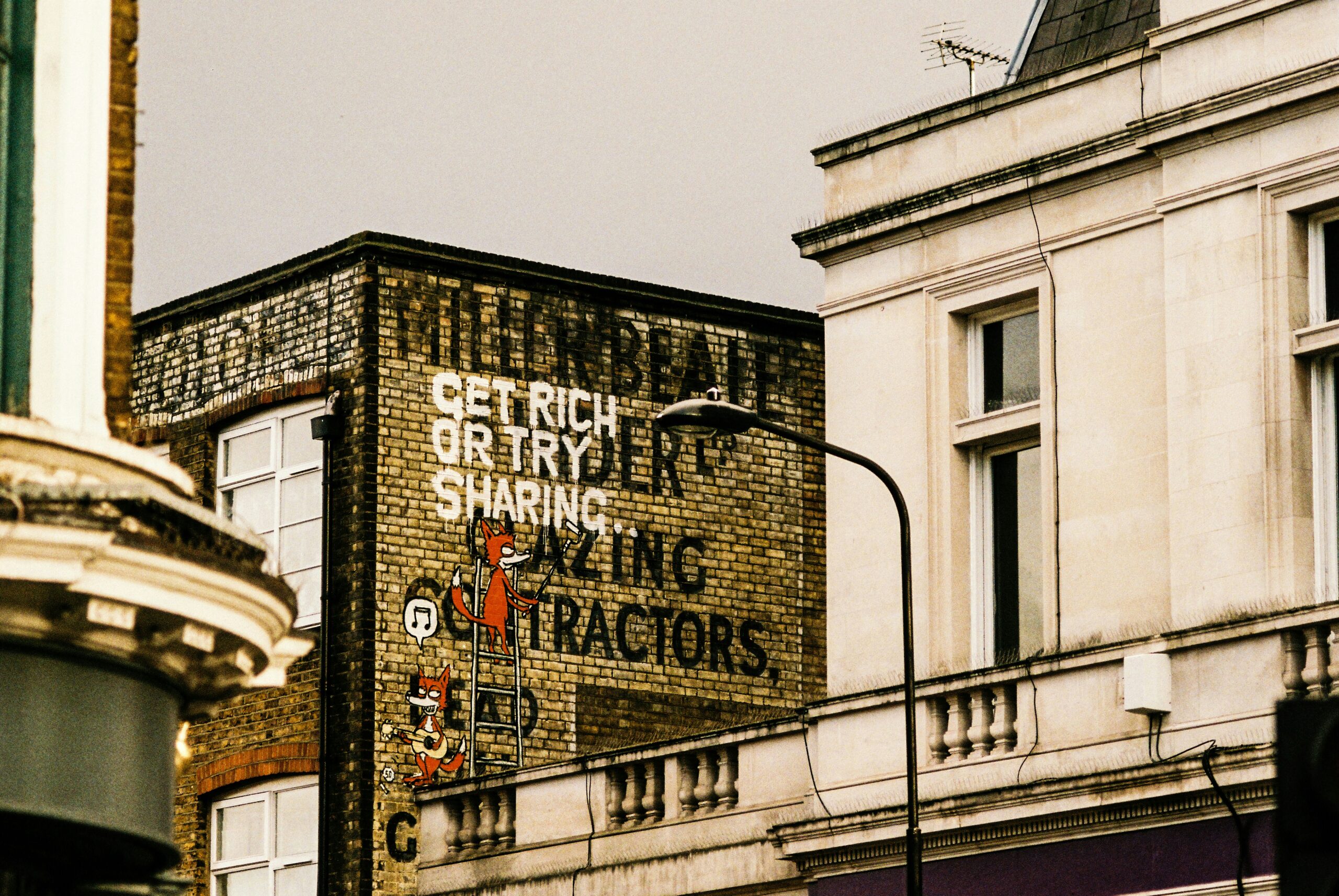 Eine Hauswand mit einem Graffiti: "Get rich or try sharing"