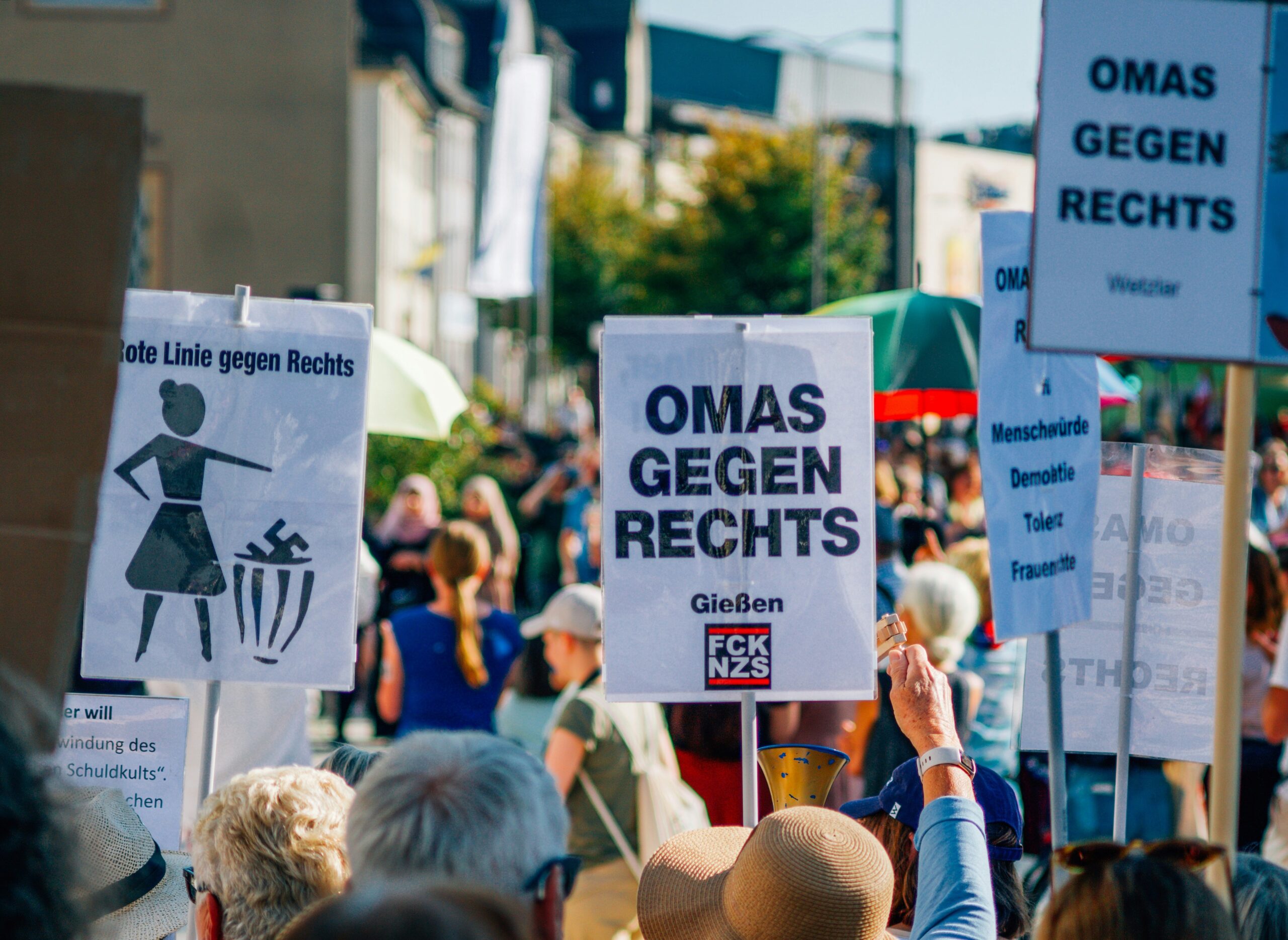 Eine Demonstration gegen Rechts, es sind hochgereckte Hände zu sehen, die Schilder der "Omas gegen Rechts" halten.