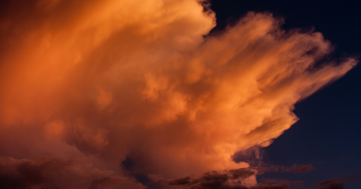 Eine große Wolke, die im Sonnenlicht orange angeleuchtet wird.