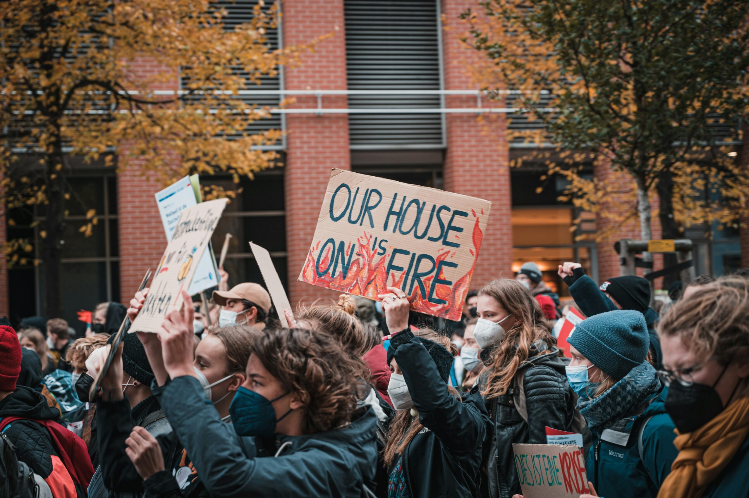 Eine Klimademo, im Fokus ein Demoschild mit der Aufschrift: Our House is on Fire.